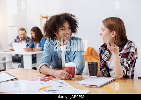 Attento ascoltatore. Due operose ha ispirato i giovani seduti a tavola in ufficio e chiacchierando eccitato circa il loro progetto mentre si beve Foto Stock