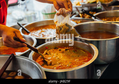 Venditore ambulante versando il curry nel sacchetto di plastica, Bangkok, Thailandia Foto Stock