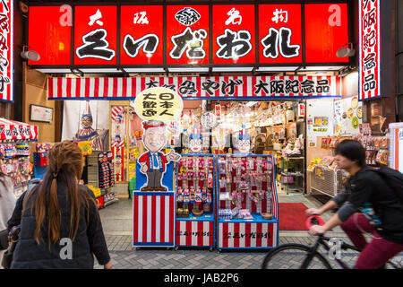 Giappone, Osaka, Dotonbori. Notte tempo. Parte anteriore del negozio di souvenir, vendita famosa icona Kuidaore Taro Clown (AKA Kuidasore Ningyo, voci Foto Stock