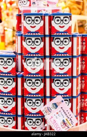 Giappone, Osaka, Dotonbori. Notte tempo. Visualizzazione impilata, vendita famosa icona Kuidaore Taro Clown (AKA Kuidasore Ningyo), gli elementi. Scatole con faccia di clown. Foto Stock