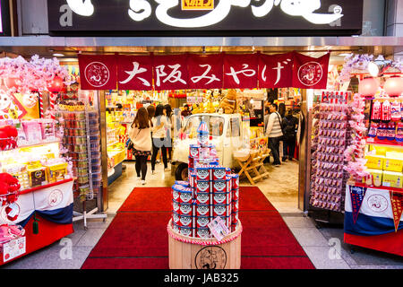 Giappone, Osaka, Dotonbori. Notte tempo. Parte anteriore del negozio di souvenir, vendita famosa icona Kuidaore Taro Clown (AKA Kuidasore Ningyo), gli elementi. Cerca in. Foto Stock