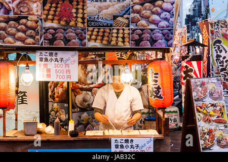 Dotonbori, quartiere dei divertimenti di Osaka. Takoyaki portar via il contatore dell'uomo con la preparazione del cibo. Notte tempo. Sign in inglese, "OK". Chochin Foto Stock