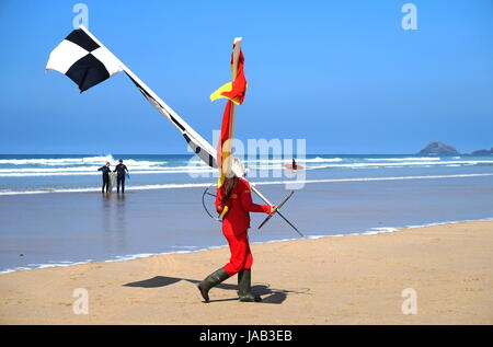 Newquay, Cornwall, Regno Unito - 7 Aprile 2017: femmina RNLI lifeguard spostando il nuoto e il surf bandiere della zona come la marea entra in Foto Stock