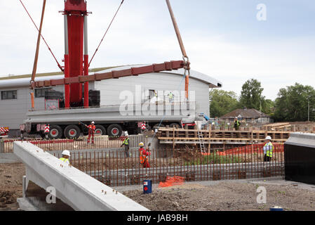 Una gru mobile solleva un grande, pre-cast trave di calcestruzzo in posizione per la costruzione di un nuovo ponte stradale a Woking, Surrey, Regno Unito Foto Stock