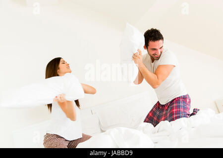 Paio di divertirsi con un cuscino lotta nel letto di casa Foto Stock