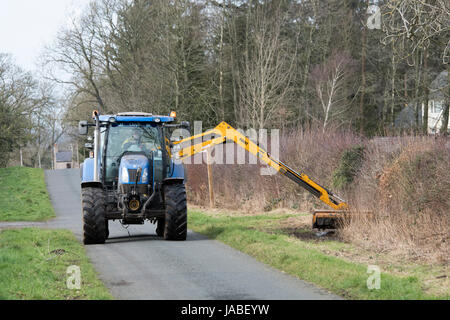 Trattore con tagliasiepi a tagliare l'erba orlo lungo una strada rurale, Cumbria, Regno Unito. Foto Stock
