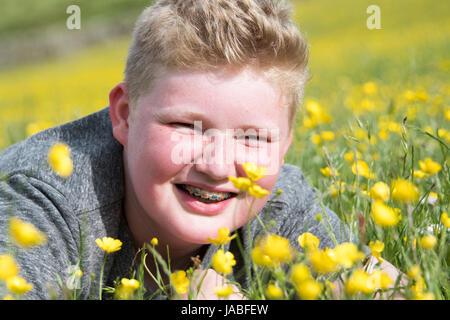 Sorridente boysat adolescente nel prato di fiori selvaggi, North Yorkshire, Regno Unito Foto Stock