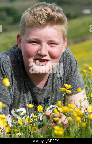 Sorridente boysat adolescente nel prato di fiori selvaggi, North Yorkshire, Regno Unito Foto Stock