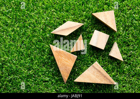 Tangram in legno puzzle attendere per completare su artificiali erba verde sullo sfondo Foto Stock