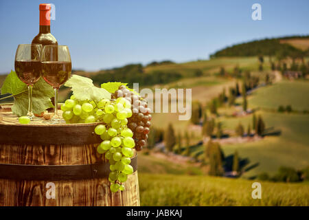 Vino rosso bottiglia e bicchiere di vino in botte barile. Bella Toscana sullo sfondo Foto Stock