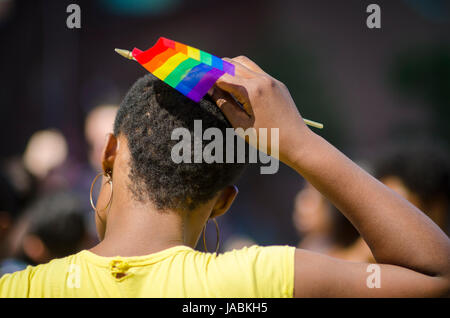 In Africa non identificabili-donna americana luoghi bandiera arcobaleno nel suo afro peli sul margine di un estate Gay Pride Parade Foto Stock