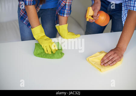 Close-up di maschi e femmine di pulizia delle mani la superficie del tavolo con strofinacci e detergente Foto Stock