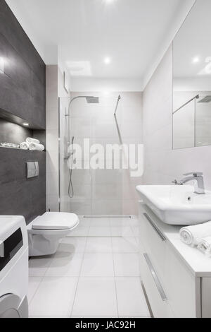Edificio moderno, bianco bagno con doccia, wc, lavabo e parete scura Foto Stock