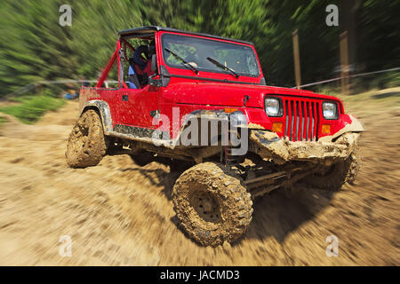 Red off-road auto in un terreno difficile. Sfondo sfocato. Tutti i potenziali registrati vengono rimossi. Foto Stock