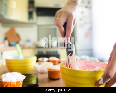 Chiudere il colpo di molti dolci tortine in primo piano mentre un baker decorare l'ultimo Foto Stock