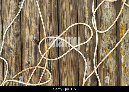 Tangled cima di ormeggio sul pavimento in legno sul molo di un porto. Foto Stock