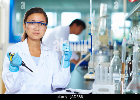Una femmina laboratorio cinese scienziato che lavora presso il laboratorio con le provette per la prova Foto Stock