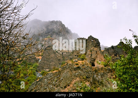 Scogliera con grotta vicino Monastero di Geghard in Armenia in caso di pioggia. Scogliere circostanti Monastero di Geghard e Azat River Gorge sono inclusi insieme con il monastero nel World Heritage Site listing. Foto Stock