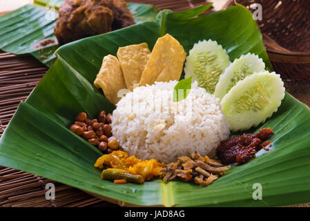 Nasi lemak, un tradizionale malay di pasta di curry piatto di riso servito su una foglia di banano Foto Stock