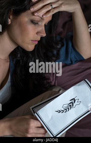 Close up ritratto di donna lutto holding necrologio Foto Stock