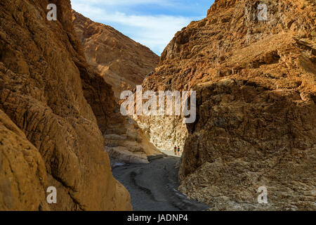 In questa schermata due escursionisti a piedi verso il basso attraverso una sezione di rame-colorato si restringe del Mosaico Canyon nel Parco Nazionale della Valle della Morte, California, Stati Uniti d'America. Foto Stock