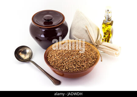 Ancora la vita di cereali di grano saraceno in ceramica pial, vaso di ceramica, vecchio cucchiaio e borsa di tela per i cereali, olio con spezie e condimenti, isolato su bianco b Foto Stock