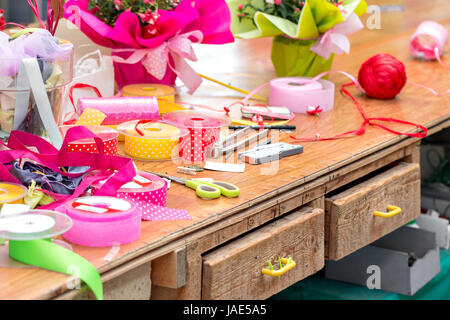 Escursioni fiorista. strumenti e vari nastri per decorazione di regali e mazzi di fiori in legno per tabella semplice Foto Stock