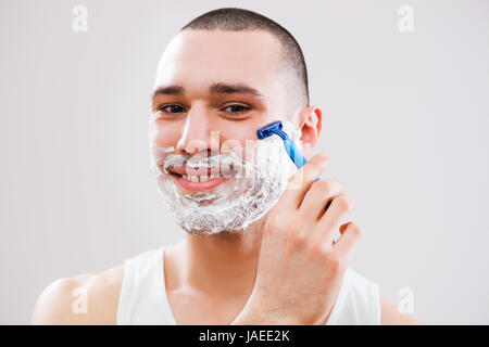 Giovane uomo è la rasatura la sua barba. Foto Stock