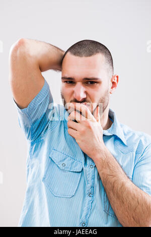 Giovane uomo è sudato e lui disgusta odore sgradevole. Foto Stock