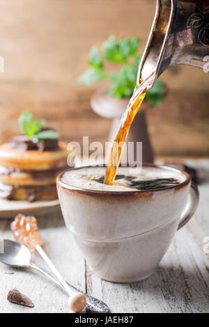 Tazza di caffè per colazione con frittelle sul vecchio sfondo di legno. Foto Stock