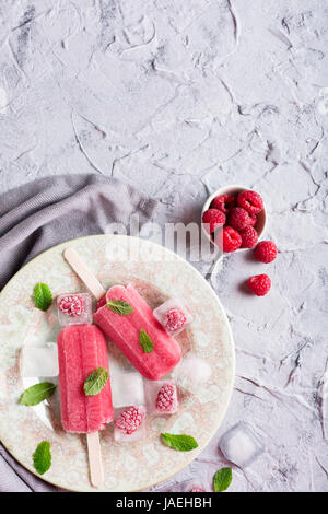 In casa lampone popsicles sulla piastra con ghiaccio e bacche. Estate concetto alimentare con copia spazio per il testo. Vista dall'alto. Foto Stock