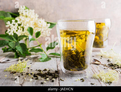 Medicina sani il tè verde con il sambuco in vetro bianco antico tavolo in legno con il sambuco rami. Copia dello spazio. Foto Stock