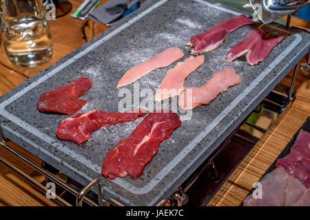 Vari tipi di carne preparati per la cottura vengono arrostite su ardesia di grafite Foto Stock