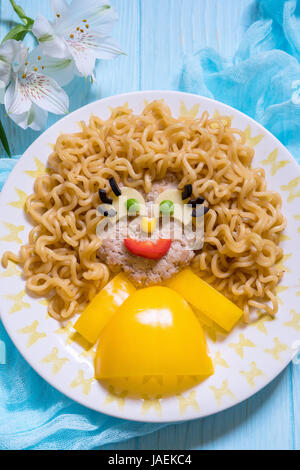 Funny Girl cibo faccia con cotoletta, tagliatelle di pasta e verdure Foto Stock