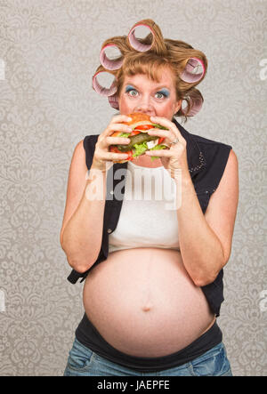 Giovani incinta Donna single mangiare un panino Foto Stock