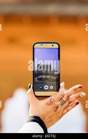 Primo piano di una donna mano azienda uno smartphone tenendo la foto di una cupola in un forte in Rajasthan, India Foto Stock