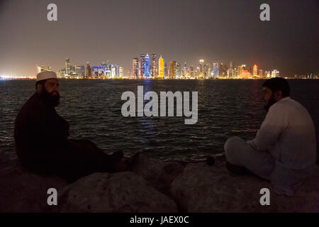 Gli amici di chat e godere della vista di tutta la baia verso l'alto luogo quartiere degli affari a Doha, in Qatar. Foto Stock