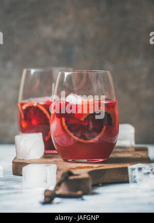 Arancio sanguigno e fragola estate Sangria. Frutta rinfrescante vino rosato cocktail in bicchieri di ghiaccio, sfondo scuro, spazio di copia Foto Stock