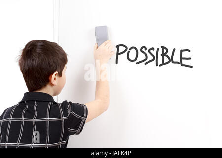 Little Boy con il bianco blank board cancellando i paragrafi dal termine impossibile Foto Stock