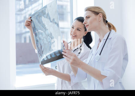 Discutendo di trattamento della malattia. Felice padronanza del concentrato di neurologi lavora presso il laboratorio medico mentre si tiene il cervello x ray immagine e godendo di discu Foto Stock