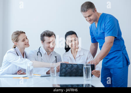 Esame delle ossa in dettagli. Coinvolti vivace esperti chirurghi traumatica lavorando e godendo la discussione durante l'analisi di raggi x scan Foto Stock