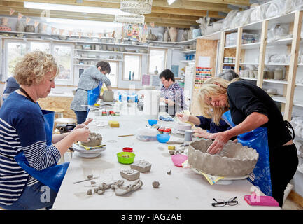 Cinque persone, donne in un studio di ceramiche, lavorando su costru zione oggetti di creta. Foto Stock