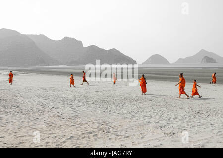 Scenario Theravada tailandese i monaci buddisti e il debuttante in giallo arancione abiti dello zafferano su una spiaggia di sabbia con gradini, montagne e natura tutto Foto Stock