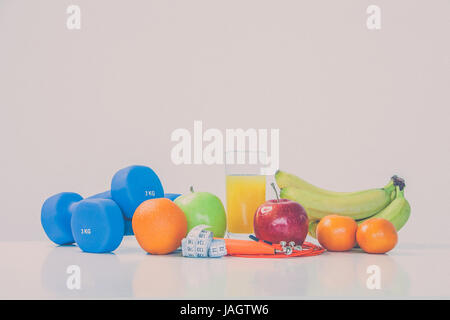 Il concetto di una dieta sana. Fintes pasti. Stile di vita sportiva. Manubri. Arance. Le mele. Banane. succo di frutta. La corda da salto. Nastro di misurazione cintola. su uno sfondo bianco. studio di ripresa. Foto Stock