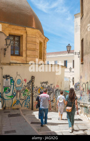 Cagliari città vecchia, i turisti a piedi attraverso un approccio fortemente graffitied Vicolo nel centro storico quartiere Marina di Cagliari, Sardegna. Foto Stock