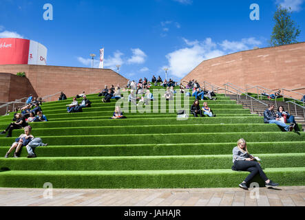 I giovani seduti al sole sui passi nelle vicinanze del Liverpool One Shopping Centre in Merseyside Foto Stock