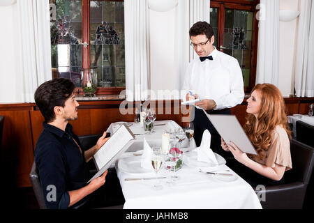 Frau und Mann beim Abendessen im Restaurant Kellner nimmt Bestellung auf Foto Stock