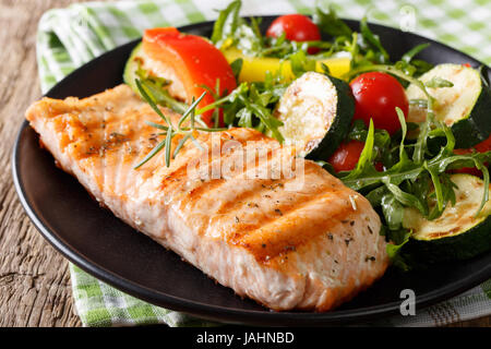Gustoso il filetto di salmone alla griglia e insalata di verdure con foglie di rucola close-up su una piastra orizzontale. Foto Stock