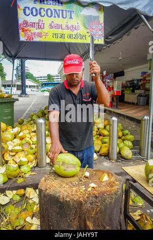 Kuala Lumpur, Malesia - 9 Marzo 2017: Sconosciuto venditore ambulante persona il taglio e la vendita di cocco fresco ai turisti. Foto Stock