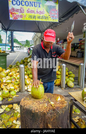 Kuala Lumpur, Malesia - 9 Marzo 2017: Sconosciuto venditore ambulante persona il taglio e la vendita di cocco fresco ai turisti. Foto Stock